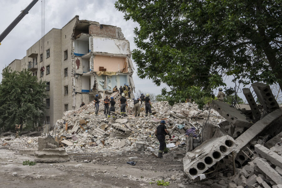 Räddningsarbetare vid rasmassor efter en raketattack mot ett bostadshus i staden Tjasiv Jar.