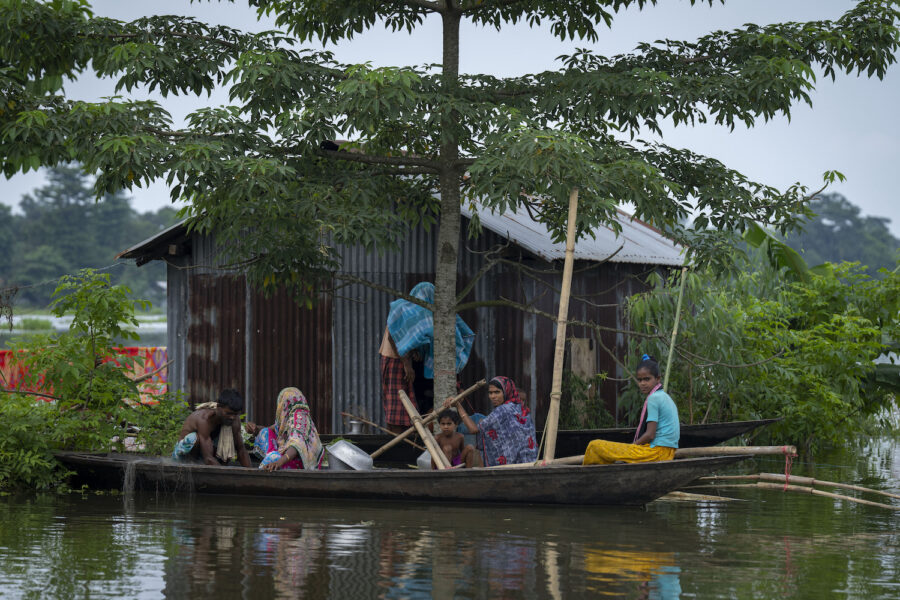 En familj i delstaten Assam i Indien lämnar sitt hem som översvämmats efter häftiga monsunregn.