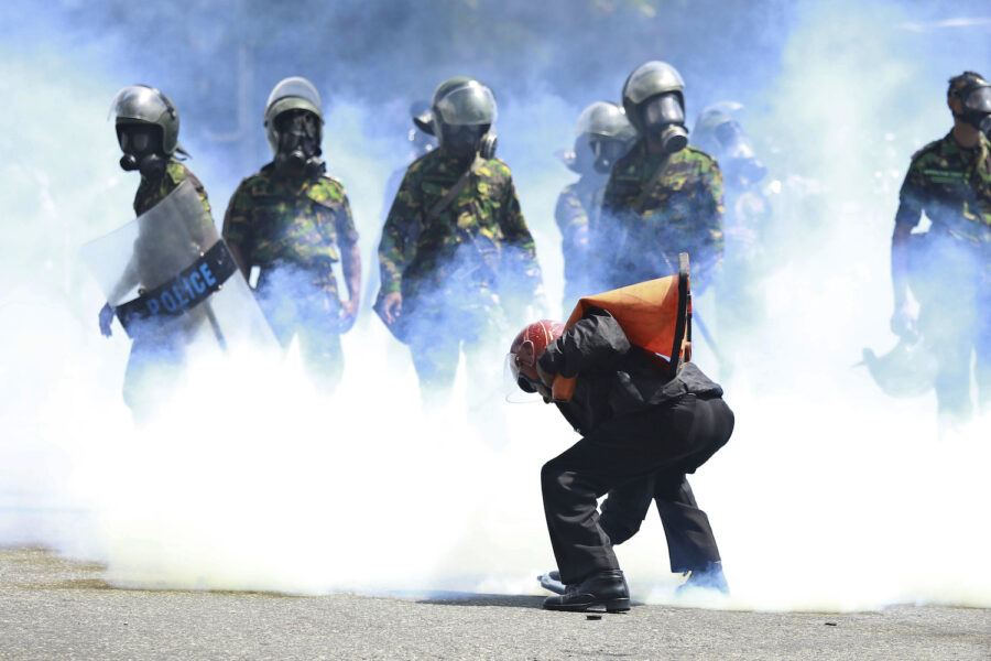 En man plockar upp en tårgasbehållare för att kasta den efter att polisen avfyrat den för att skingra demonstranterna i Sri Lankas huvudstad Colombo.