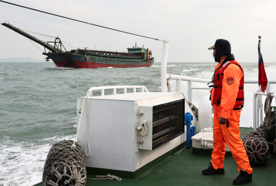 En taiwanesisk kustbevakare betraktar ett Kinaflaggat muddringsfartyg utanför Matsuöarna.