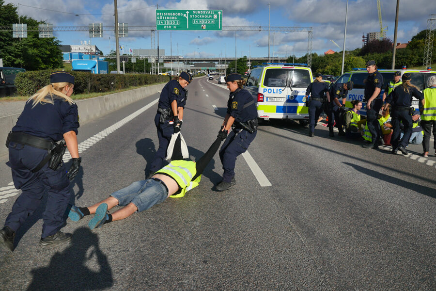 Polis släpar bort en aktivist från måndagens aktion på en motorväg i Stockholm.