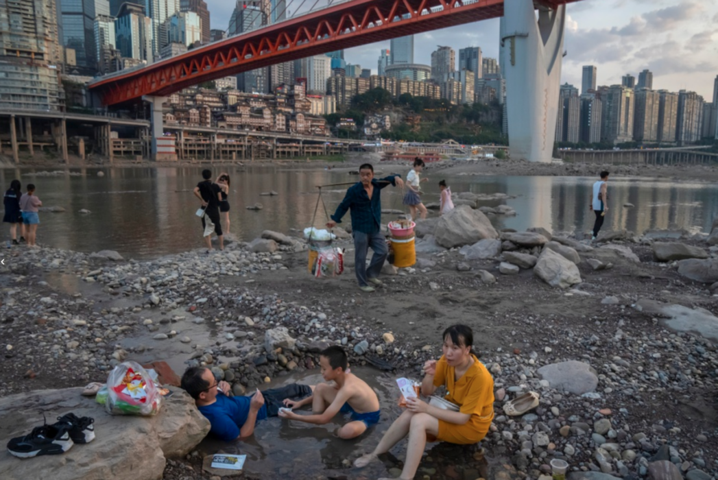 Boende i staden Chongqing försöker svalka sig i pölar som bildats i Jialingfloden, en biflod till Yangtze, när vattennivån sjunkit undan.