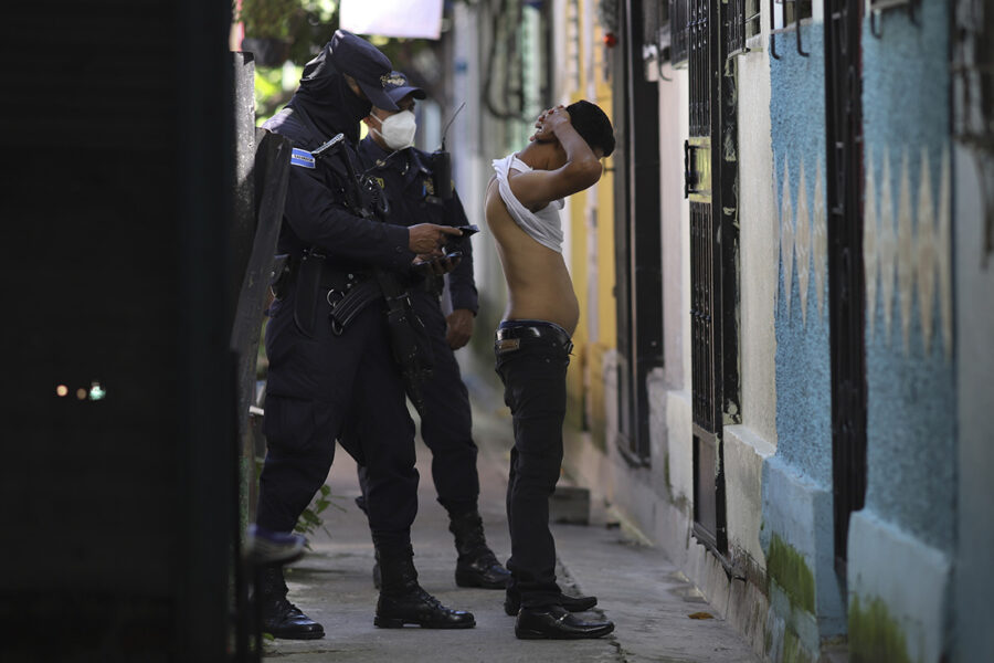 Poliser kroppsvisiterar en man under en sökinsats efter gängmedlemmar i Soyapango utanför San Salvador den 16 augusti.