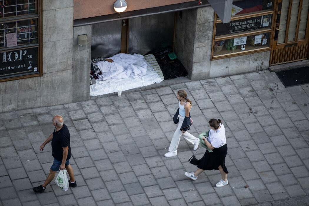En hemlös person sover utanför en port i Stockholm.