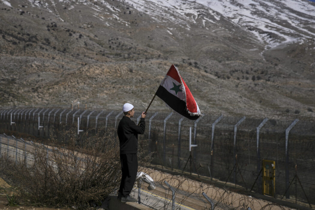 En ung drusisk man håller upp en syrisk flagga vid Golanhöjderna, som Israel kontrollerat sedan 1967, under en protest med syfte att få Israel att lämna tillbaka marken till Syrien.