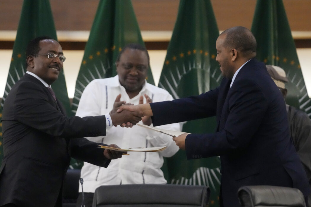 Regeringens förhandlare Redwan Hussein skakar hand med Tigrayrebellernas förhandlar Getachew Reda medan medlaren Uhuru Kenyatta applåderar.