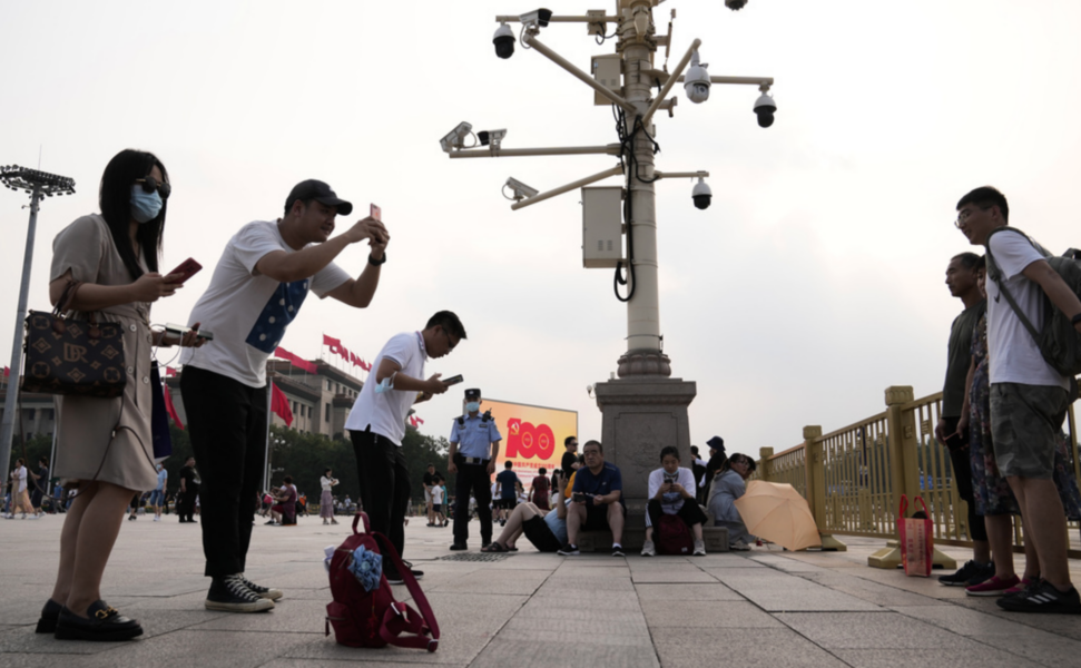 Besökare tar bilder på Himmelska fridens torg, under en mängd övervakningskameror.