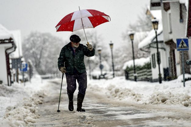 En man gömmer sig från snöflingorna under ett paraply i Burguete i norra Spanien nu i januari.