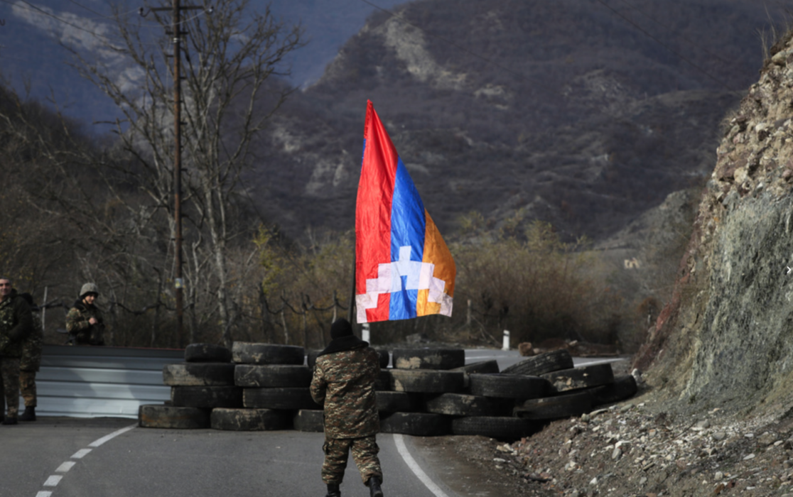 En soldat från Nagorno-Karabach bär den självutropade republiken Artsachs flagga vid en gränskontroll i regionen i november 2020.