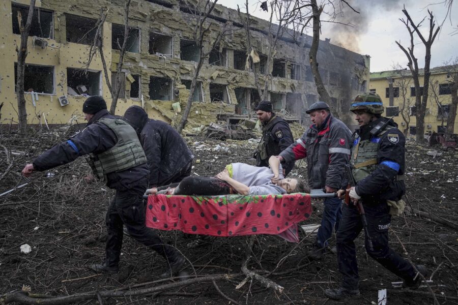 Ukrainska räddningsarbetare bär iväg en skadad och gravid kvinna från den attackerade förlossningskliniken i Mariupol, den 9 mars förra året.