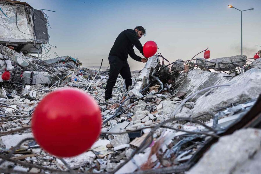 Ogun Sever Okur sätter ut röda ballonger på byggnader som rasat i den svårt skalvdrabbade staden Antakya.