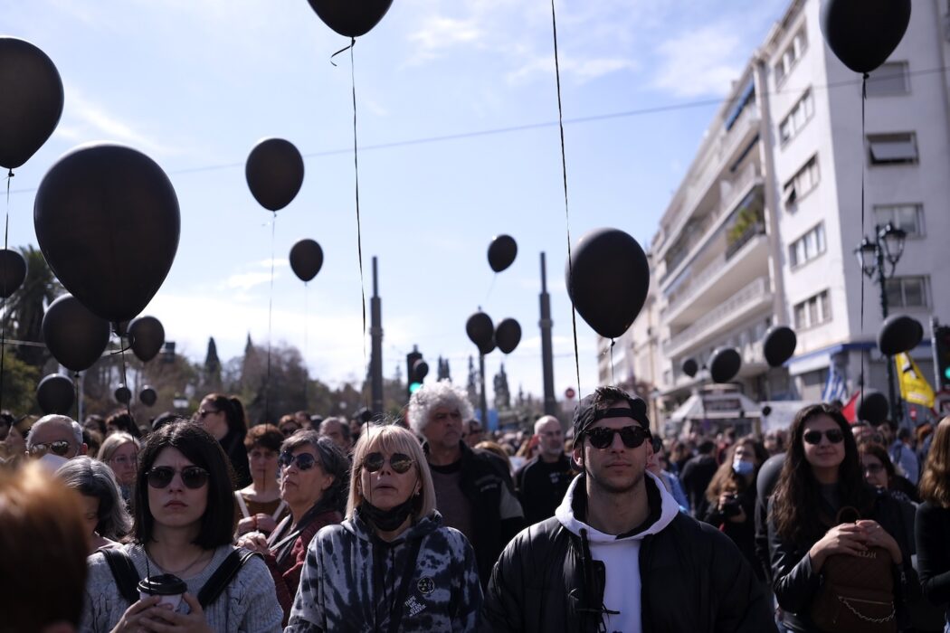 Demonstranter med svarta ballonger håller en tyst minut utanför parlamentsbyggnaden i Aten.