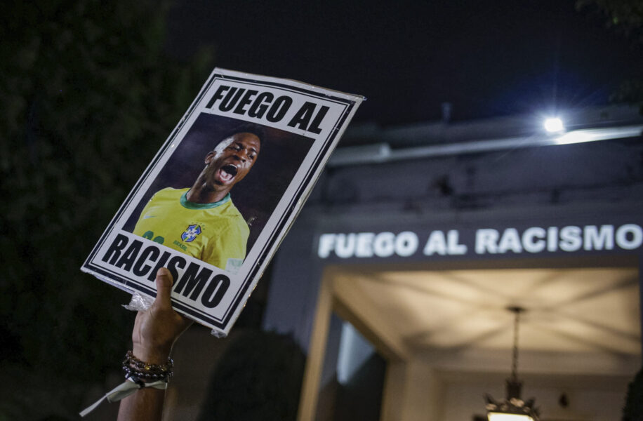  En demonstrant håller upp ett plakat på fotbollsstjärnan Vinicius Jr utanför det spanska konsulatet i Sao Paulo med budskapet "stoppa rasismen".