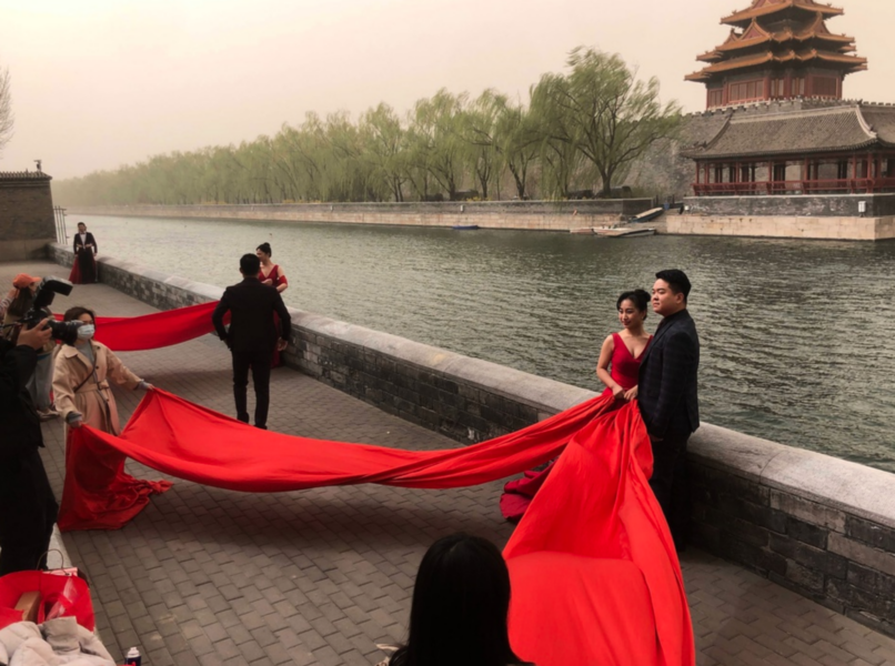 Nygifta par poserar vid Förbjudna staden i Peking.