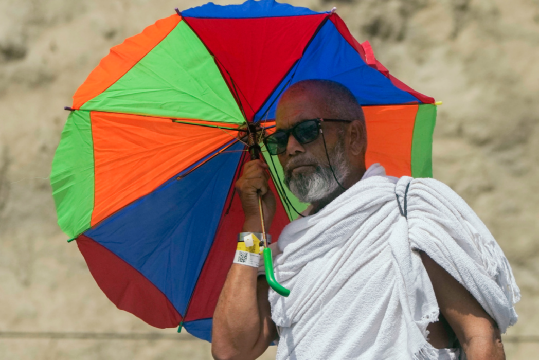 En pilgrim skyddar sig mot solen under hajj.
