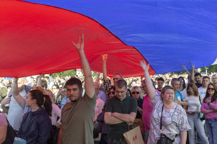 Demonstranter håller upp den serbiska flaggan under en massprotest mot regeringen i huvudstaden Belgrad på lördagen.