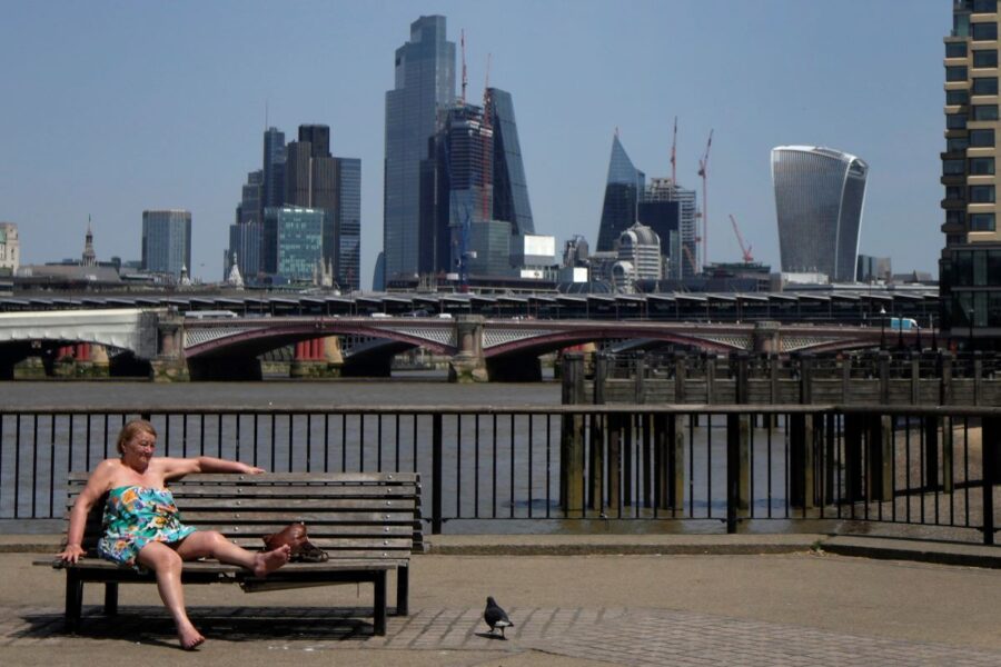 En kvinna solbadar framför floden Thames i London under den rekordvarma värmebölja som drabbade Storbritannien under juni i år.