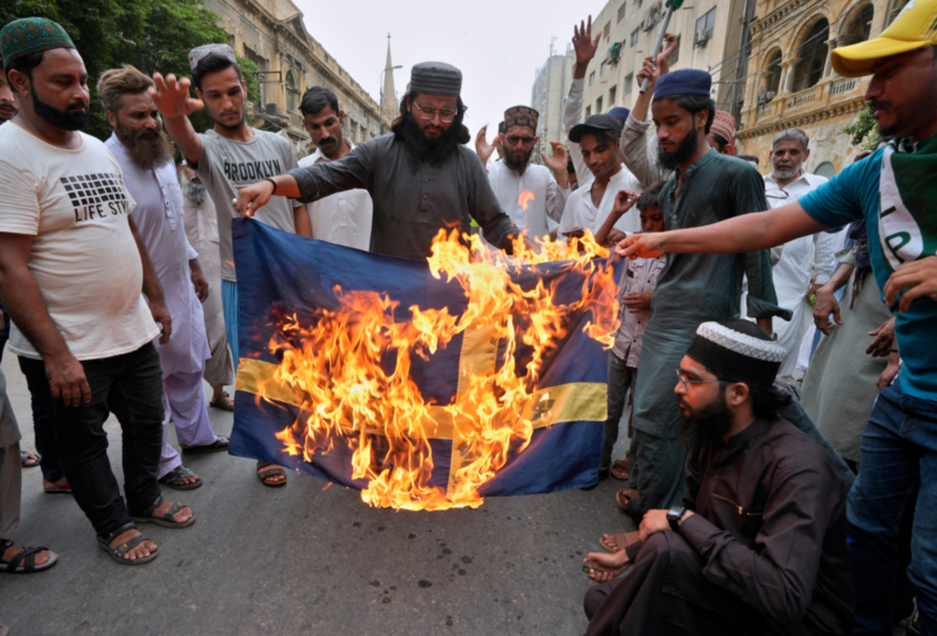 Anhängare till det radikala islamistpartiet Tehreek-e-Labiak bränner en svensk flagga i Karachi.
