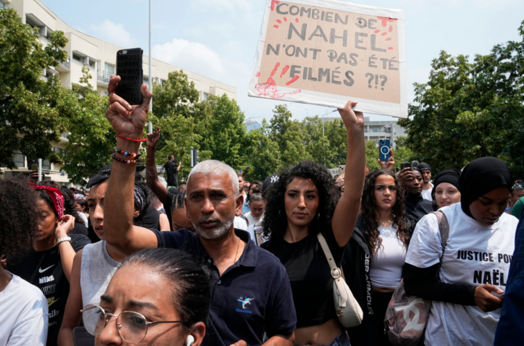 "Hur många Nahel har inte filmats?" Så står det på det plakat som en demonstrant håller upp efter att en 17-årig pojke skjutits till döds av polis i Frankrike.