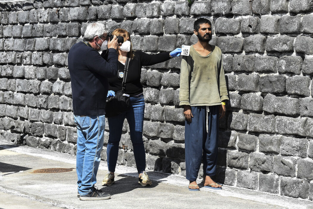 En migrant fotograferas för identifiering i hamnen i Catania på Sicilien.