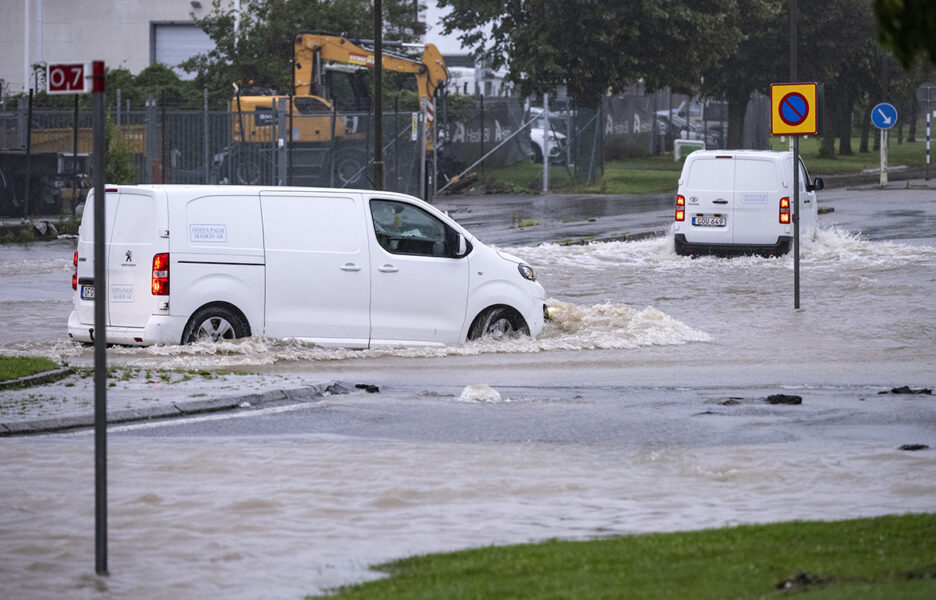Bilar försöker ta sig genom en översvämmad rondell i Arlöv vid den avstängda, översvämmade Västkustvägen E6 utanför Malmö.