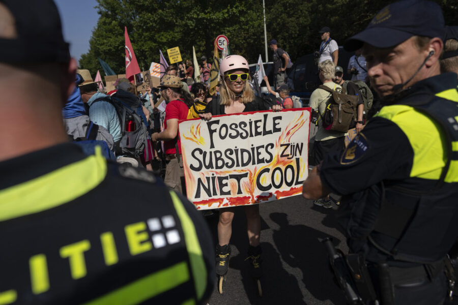 En aktivist i Haag med plakatet "Subventioner av fossilbränsle är inte coolt”.