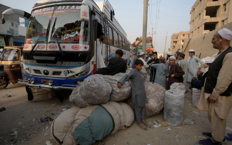 Flyktingar samlas vid bussar som ska avgå mot Afghanistan i den pakistanska storstaden Karachi.