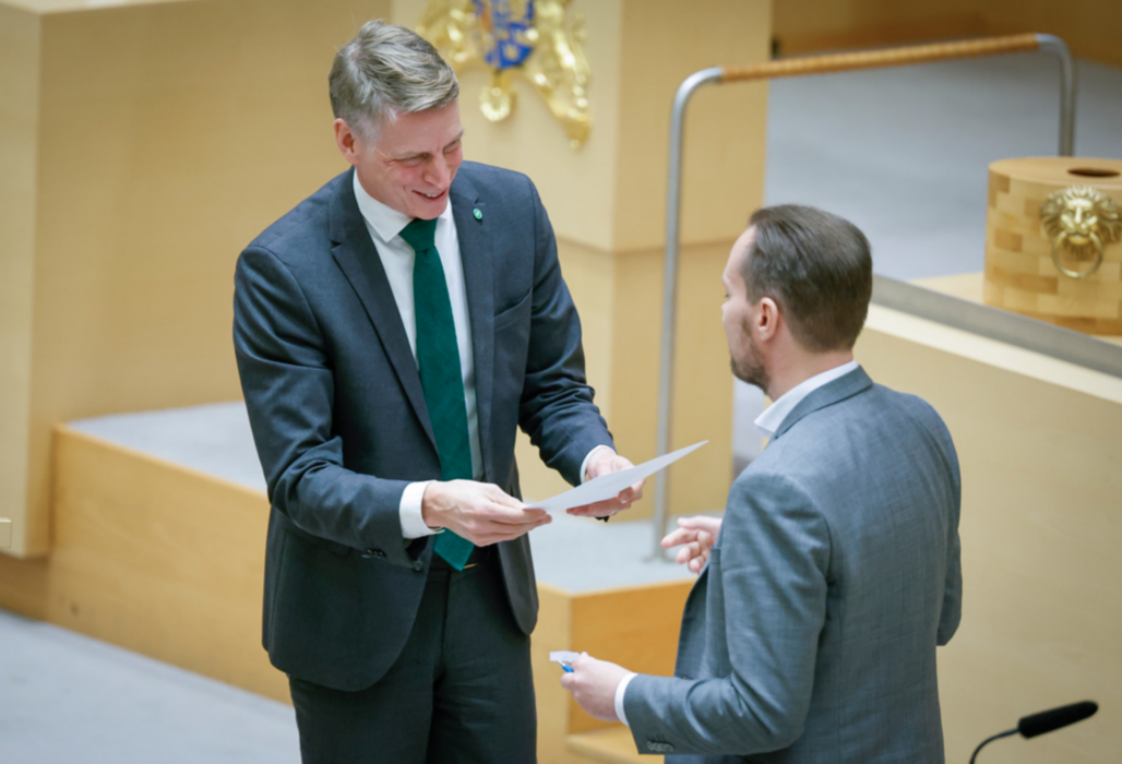 Miljöpartiets språkrör Per Bolund tackas av och får present av Sverigedemokraternas Martin Kinnunen (SD) under en EU-politisk partiledardebatt i riksdagen på onsdagen.