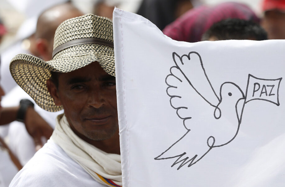 En rebell från Colombias revolutionära väpnade styrkor, Farc, med en vit fredsflagga under en manifestation 2017 för att fira att fredsförhandlingen är i hamn.