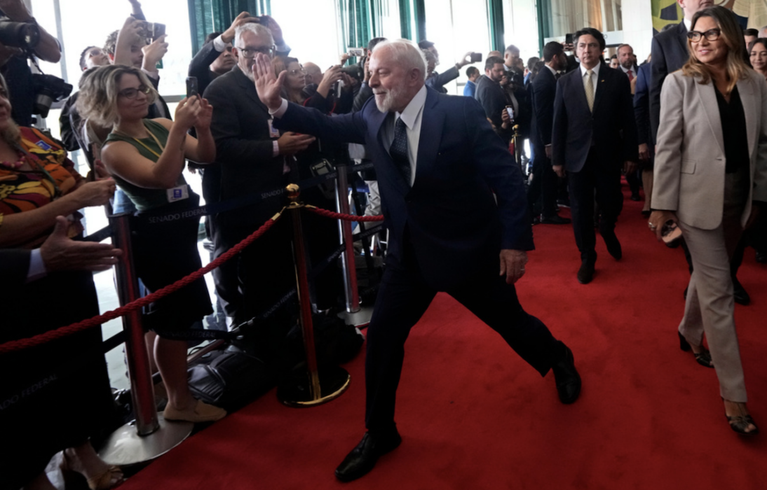 Brasiliens president Luiz Inácio Lula da Silva hälsar på journalister när han besöker kongressen, som utsattes för ett kuppförsök för ett år sedan.