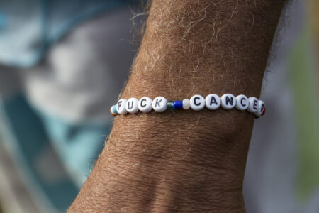 En man bär ett armband där det står "Fuck cancer".