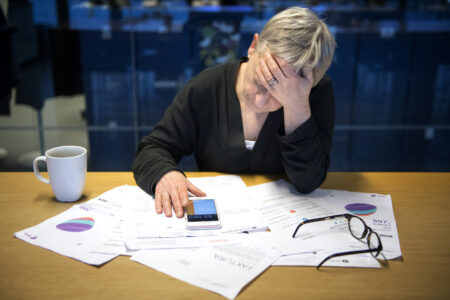 En kvinna sitter böjd över räkningar