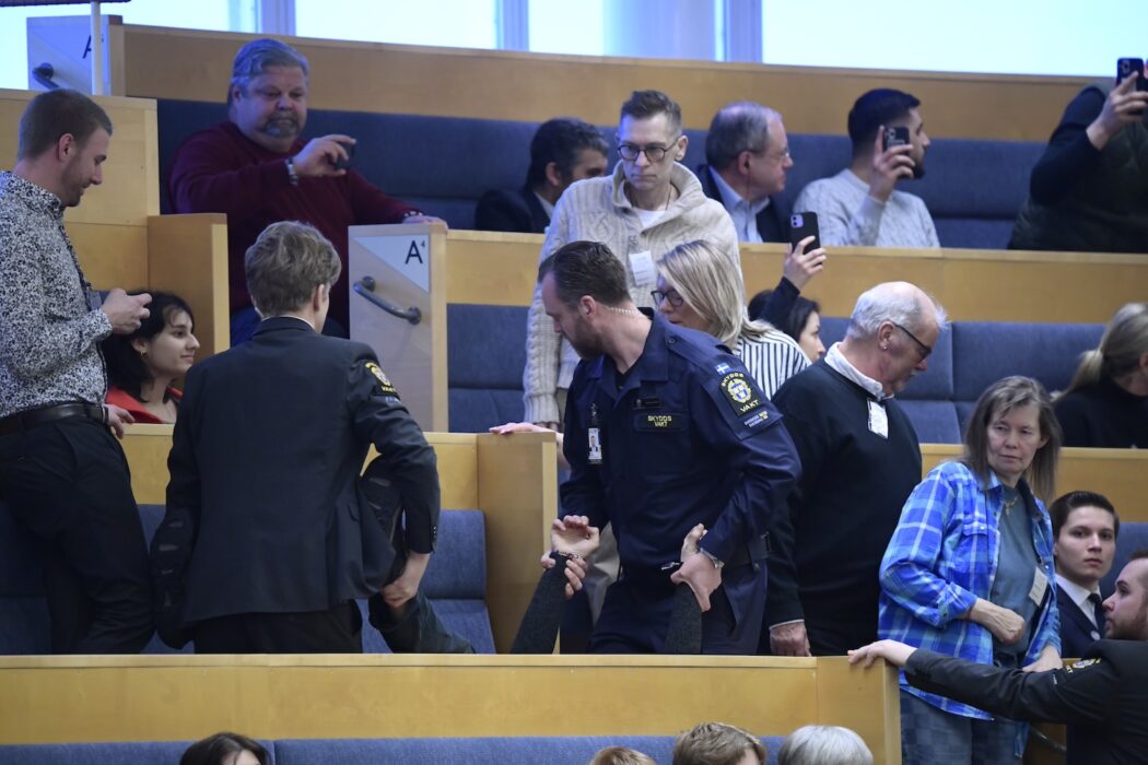 Riksdagens vakter bär iväg en person som demonstrerar under utrikespolitiska debatten.