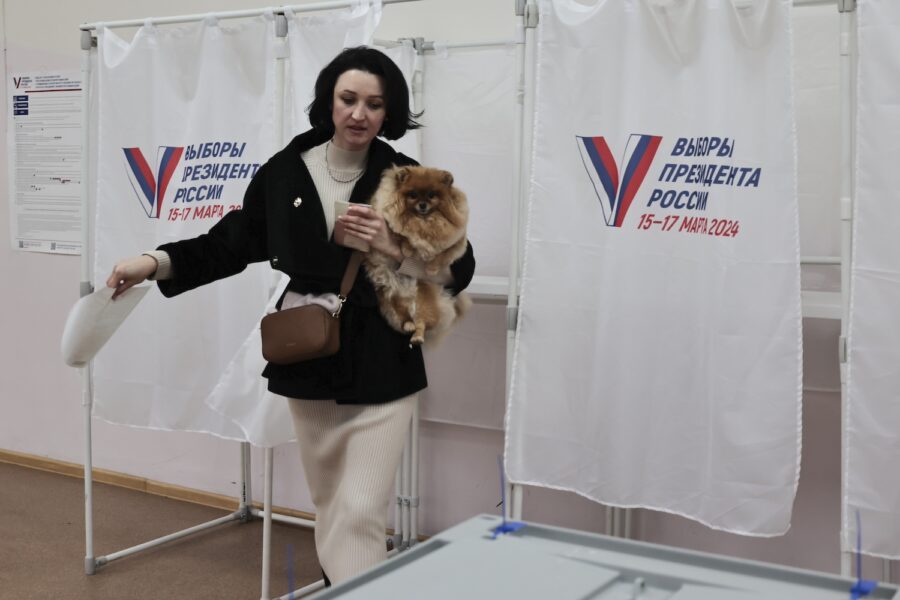 En kvinna håller i sin hund efter att ha besökt en vallokal i Vladivostok.