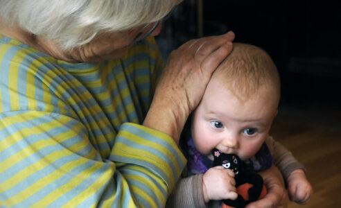 Gammal dam klappar bebis på huvudet