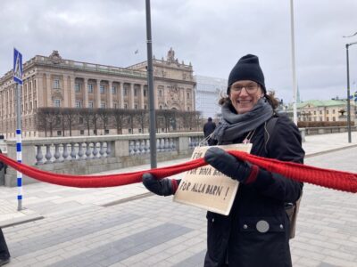 Rebellmamma håller i röd halsduk.