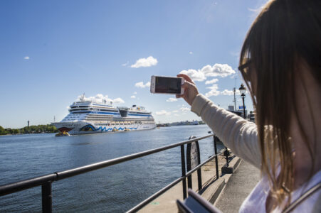 En kvinna fotograferar ett kryssningsfartyg.