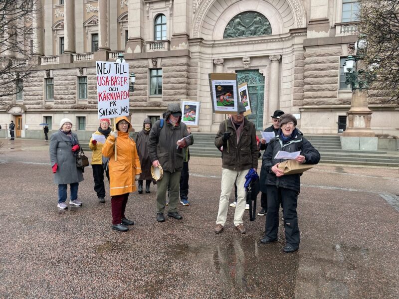 Demonstranter står utanför riksdagen kritiska mot DCA-avtalet med USA.
