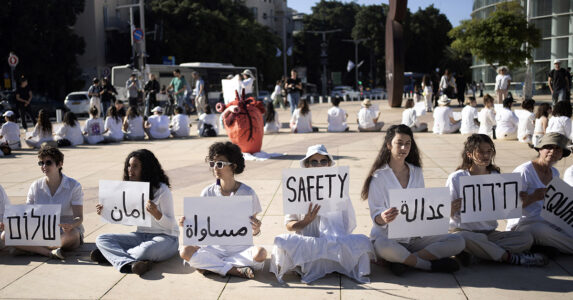 På ett torg i Tel Aviv sitter vitklädda kvinnor i ring med ryggarna mot varandra. De har plakat där det står ”fred”, ”rättvisa”, ”jämlikhet", ”säkerhet” med mera på arabiska, engelska och hebreiska.