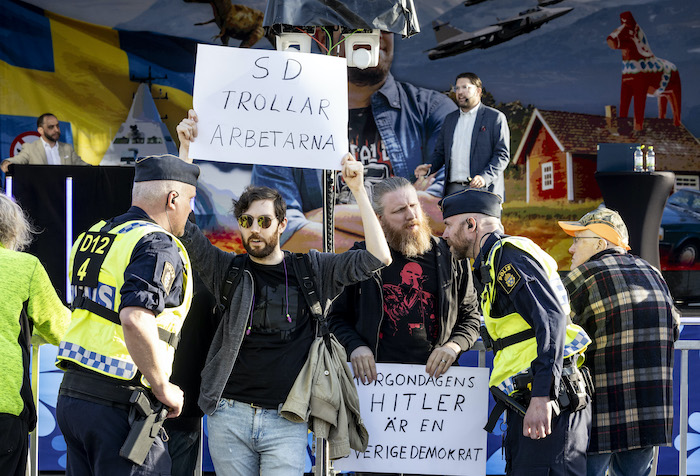 Motdemonstranter mot SD med skyltar om trollfabriken.