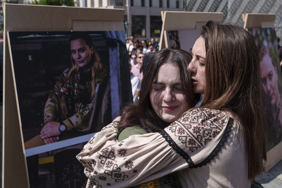 Två kvinnor håller om varandra framför porträttet av Iryna Tsybukh under dennas begravning