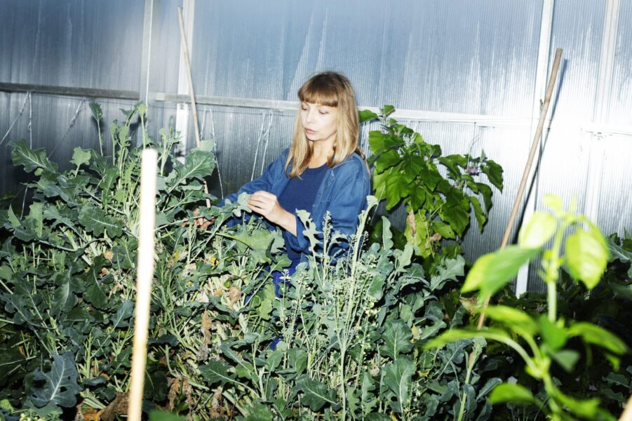 Maja Alskog Bredberg står i ett växthus med olika plantor.