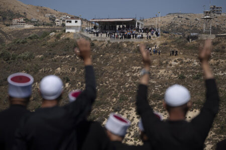 Drusiska präster fotade bakifrån, vinkandes. Berg och byggnader.