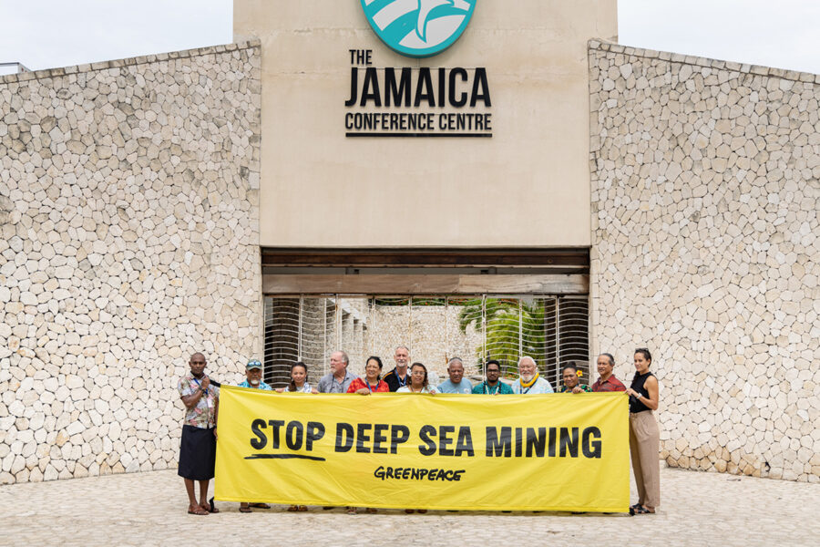 Människor håller banderoll med texten Stop deep sea mining framför The Jamaica conference center