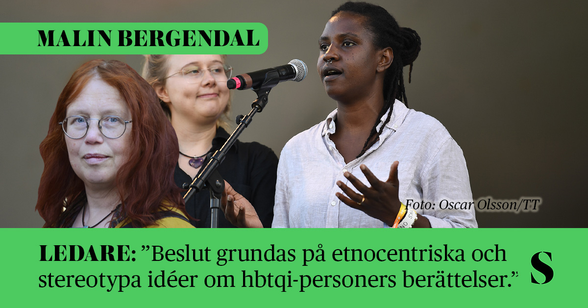 Två kvinnor på en scen – en mörk kvinna som talar i en mikrofon och en ljus kvinna som tittar på henne. Skribenten i förgrunden.