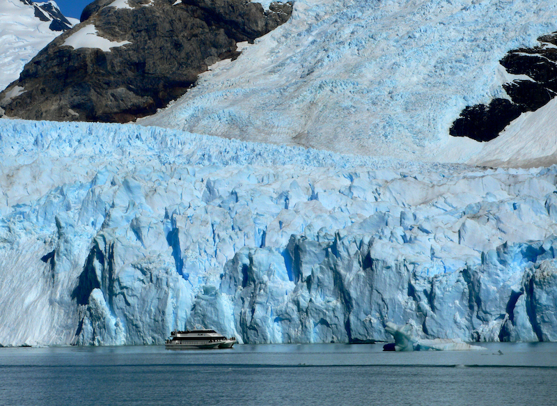 Stor glaciär vid havet. Båt framför