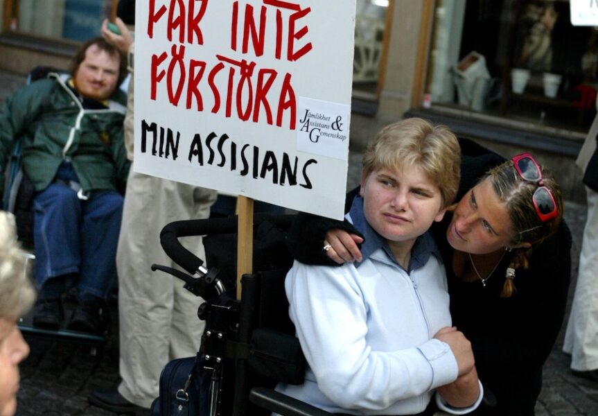 Rullstolsburen person med personlig assistent under en demonstration