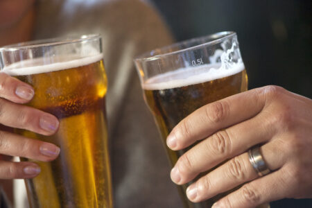 två händer med ölglas