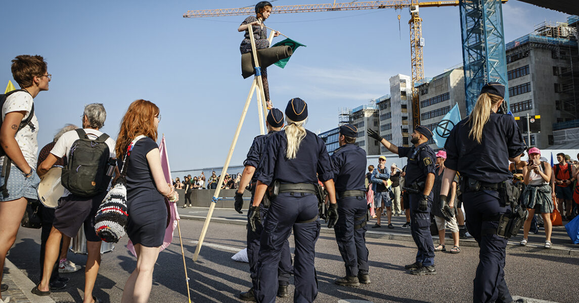 Poliser pratar med klimataktivister som blockerar en gata.