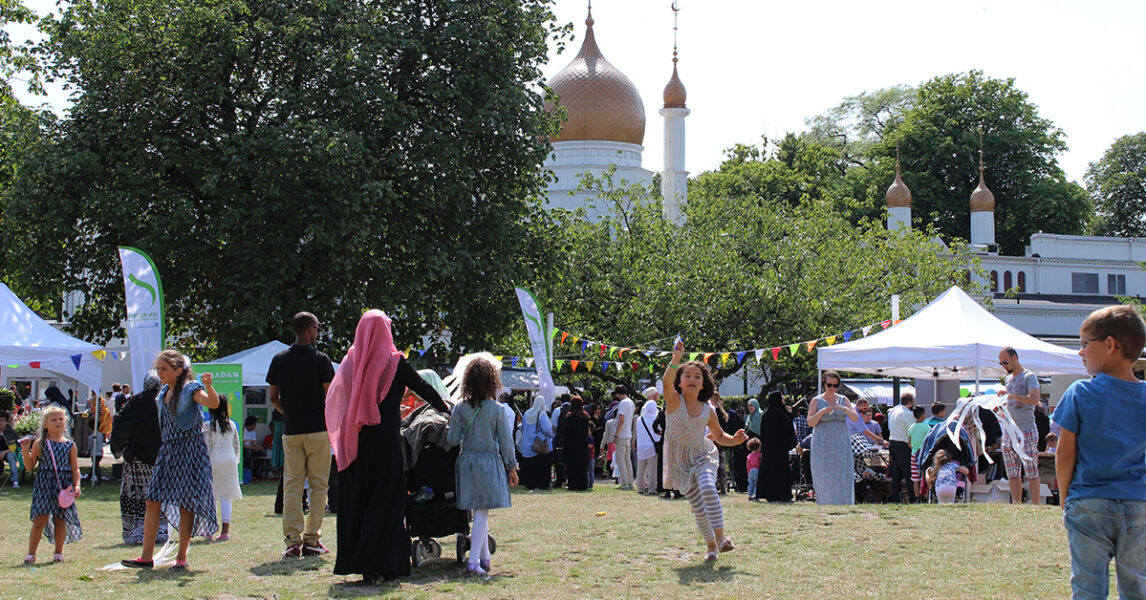 Familjefest i en park. En moské syns i bakgrunden.